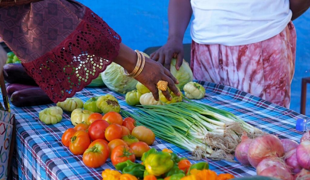 une femme noire qui veut acheter des tomates et oignons