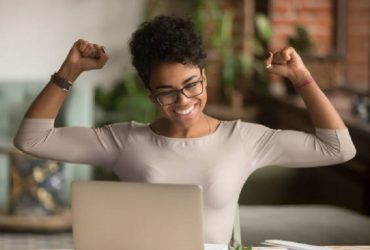 Excited happy african american woman feeling winner rejoicing online win got new job opportunity, overjoyed motivated mixed race girl student receive good test results on laptop celebrating admission